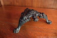 Side angled view of ornate Victorian cast iron stand showing one leg and decorative detailing on the top and leg.