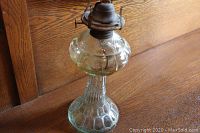 Full view of the green depression glass kerosene oil lamp base with original brass wick holder on top, showing textured base and middle section with metal wick holder.