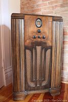Full front view of restored wooden cabinet with art deco design, vertical column detail, chevron style speaker grill, and oval dial window.