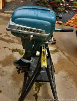 Side view of blue Evinrude 7.5 hp outboard motor mounted on a stand, showing the motor body, handle, and propeller.