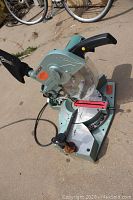 Front angle view of Hitachi chop saw showing handle, blade, and dust collection bag.