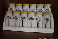 Front image showing the complete set of 12 milk glass spice jars with yellow lids in a white milk glass rack.