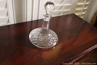 Side view of Waterford crystal ship decanter with stopper in place on polished wood surface.