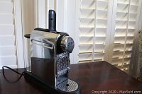 Side view of Nespresso Citiz espresso machine showing stainless steel body and water reservoir.