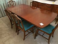 Overall view of rectangular vintage wooden dining table with six matching chairs.