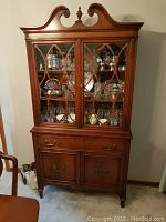 Full view of vintage china cabinet showing wood lattice glass doors and decorative crown top