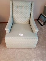 Front view of green upholstered arm chair with tufted backrest and patterned fabric, showcasing excellent condition.