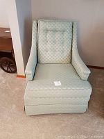 Front view of green upholstered armchair showing button tufted backrest, armrests, and cushioned seat.
