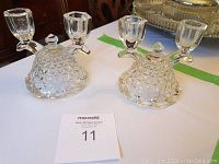Two double crystal candle stick holders on a white surface with auction card number 11 in front.