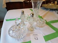 Crystal vase, salt and pepper shakers, candy dish, and candle holders arranged on table with green tape marking.