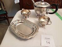 Silver plated tea set displayed on table, includes teapot, creamer, sugar bowl, and tray.