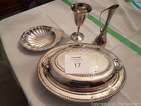 Photo of silver plated oyster tray, vase, two goblets, vegetable container with glass liner visible beneath cover