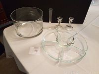 All items displayed together on a white surface: a large glass bowl, two candle holders, a slim glass vase, and a clear plastic segmented vegetable tray.