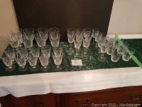 38 pieces of crystal glassware with pinwheel cut pattern arranged on green cloth, showing all items.