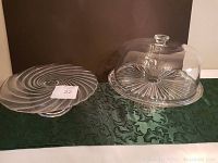 Two glass cake plates; one clear glass plate with lid and one without lid, both with textured radial patterns.