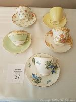 Top view of five fine bone china cups and matching saucers, each featuring different floral designs and gold trim.