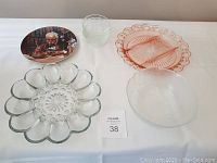 Full view of all items including Norman Rockwell plate, glass serving dishes, devilled egg tray, and custard cups on a white surface.