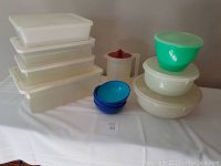 Photo showing all items: five white rectangular storage containers stacked, round mixing bowls with lids, small blue bowls, and small pitcher with red lid.