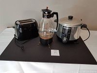 Overview of three items: toaster, deep fryer, and coffee warmer on a black surface.