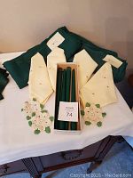 Overall display of all items: 2 green tablecloths, 4 yellow embroidered napkins, 3 crochet doilies, and boxed green candles.
