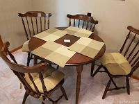 Full view of round wooden kitchen table with four cushioned chairs arranged around it, showing tabletop and chair design.