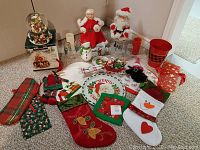 Overview of miscellaneous Christmas decorations including stockings, figurines, glassware, and fabric items