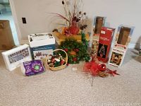 Wide view of lot showing boxed Christmas lights, greenery decoration, basket with ornaments, and stacked boxes