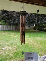 Large copper tube wind chime hanging outside with six tubes and round top
