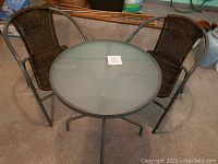 Full set of round glass top table with 2 chairs, showing overall condition and setup.