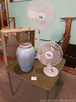 Photo showing all three electric fans and ceramic vase on a green table