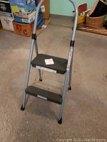Full view of metal 2-step stepstool with handlebar in a room.