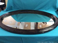 Top view of the large oval wood framed mirror showing the glass and frame condition