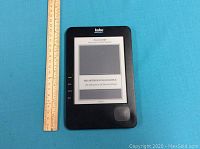 Front side of Kobo e-reader showing screen with book opened and navigation button