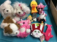 Photo shows multiple stuffed toys arranged including dogs, unicorn, and cartoon characters.