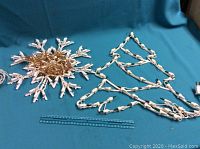 Christmas tree and snowflake light decorations arranged on a blue cloth with a ruler for size reference.