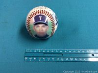 Baseball showing printed photo of Alex Rodriguez wearing Texas Rangers cap with ruler for scale