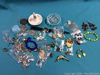 Various costume jewelry items displayed on a blue surface, including bracelets, earrings, brooches, and pins.