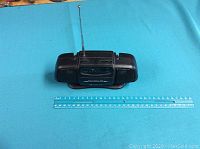 Full view of mini radio with extended antenna and ruler showing size.