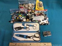 Multiple bags of assorted buttons, scissors case with scissors, and two small containers of fasteners