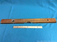 Full length view of the wooden level on a blue fabric background showing the level's body and spirit vial at one end with a metal fitting.