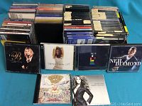 Photo showing a large number of used music CDs arranged in rows with visible cover art for Barbra Streisand, Sheryl Crow, Neil Diamond and other artists.