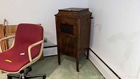 Overall front view showing Vocaloin Victrola phonograph in wooden cabinet with crank handle and louvered grille