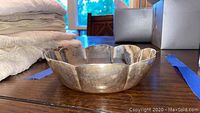Side view of scalloped sterling silver bowl on wood table