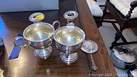 Two Gorham weighted sterling silver candle holders, Hamilton weighted sterling sugar and creamer, and sterling tea strainer on wooden table