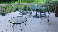Wide view of wrought iron outdoor patio furniture on deck with chairs and tables