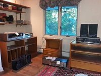Room overview showing multiple audio components on wood shelving and on floor.