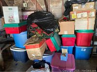 Stack of plastic holiday storage bins with boxes and black garbage bags containing decorations