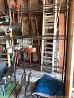 Front view of black metal shelving unit with items on shelves removed except boots and blanket at bottom.