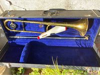 Open carrying case with trombone inside next to the white and red buffer attached to slide.