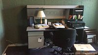 Office desk with overhead storage and filing compartments, some papers on desk